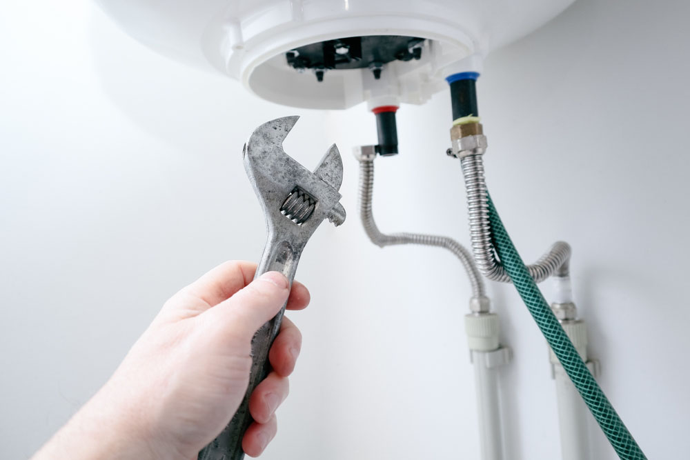 Bell Plumbing technician flushing a water heater